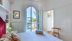 Ein Schlafzimmer mit Bett, Stuhl, Heizkörper, Fenster und Tür.