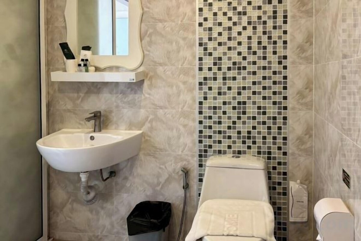 A bathroom with a sink, mirror, and tiled shower wall.