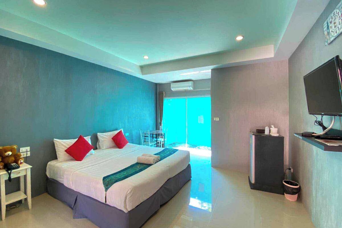 A modern hotel room with a large bed, a TV, and a desk.