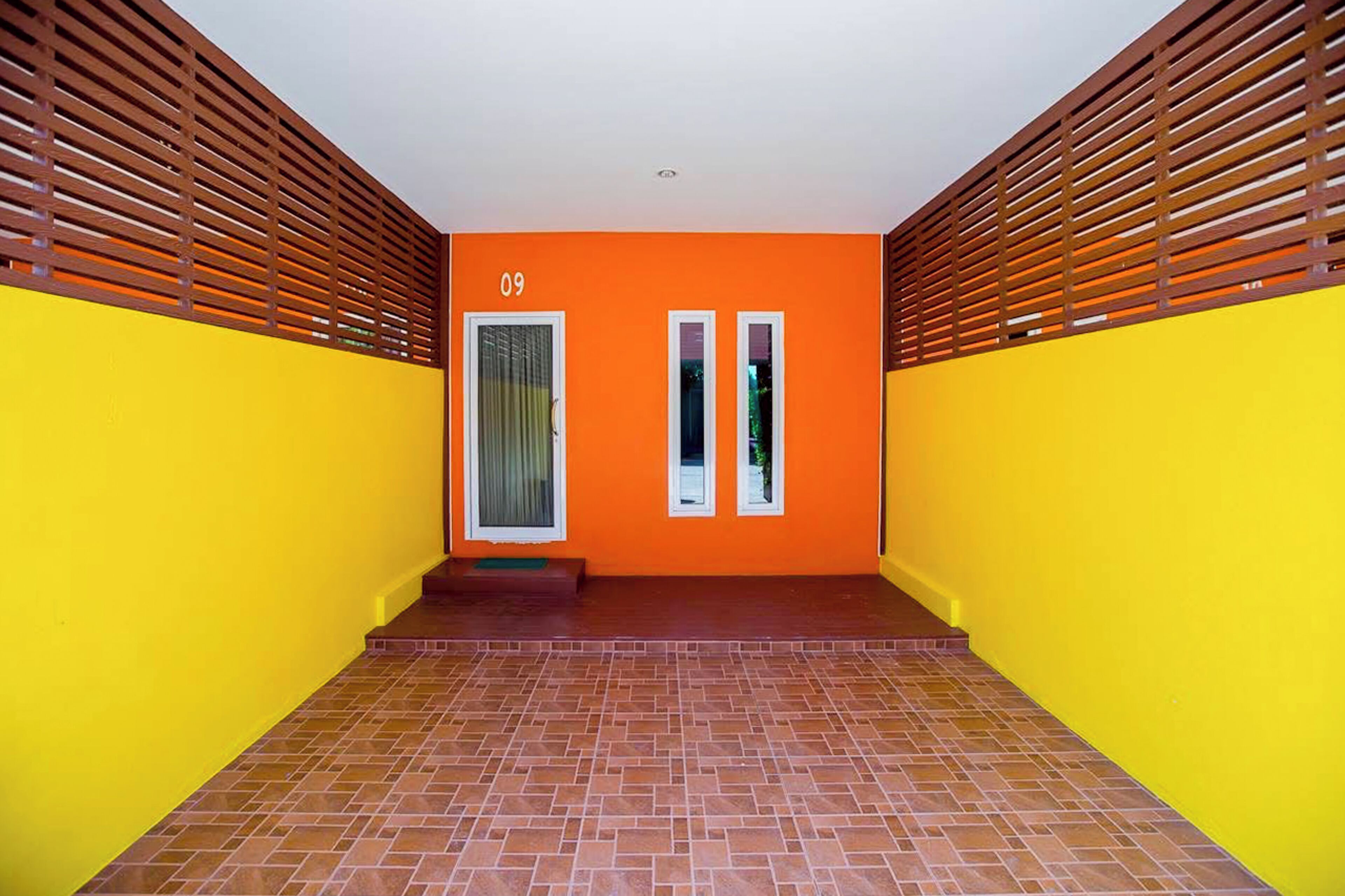 A hallway with orange walls, a number '09' above a door, and a tiled floor.