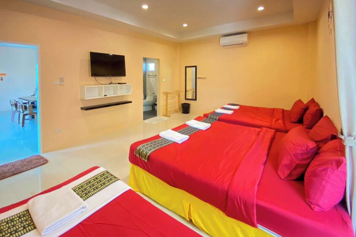 A hotel room with two beds, a TV, a mirror, and a bathroom visible through an open door.