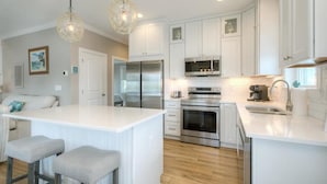 A modern kitchen with white cabinetry, stainless steel appliances, and a central island with bar stools.
