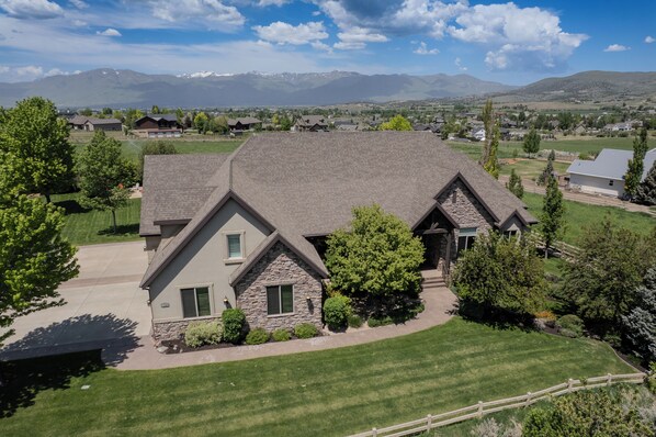 A two-story house with a stone facade, a sloped roof, and a well-maintained lawn.