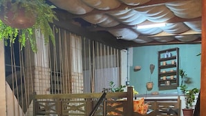 Una terraza de madera con barandilla, un banco y una planta colgante.