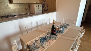 Un comedor con una mesa dispuesta para cuatro personas, una botella de champán y un camino de mesa decorativo.