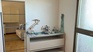 Una habitación con un armario espejado, un pequeño escritorio con adornos y vistas a través de un ventanal.