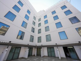 Un bâtiment moderne à plusieurs étages, doté de grandes fenêtres et d’une cour intérieure avec des portes en verre.