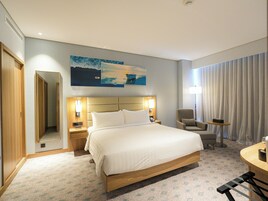 Une chambre d’hôtel avec un grand lit, une chaise, un bureau et un tableau au mur.