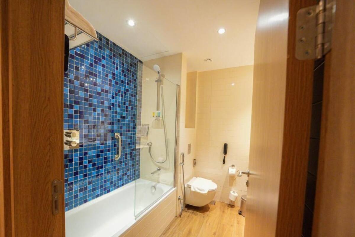 A bathroom with a glass-enclosed shower, a white bathtub, and a toilet.