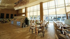 A spacious restaurant with wooden floors, large windows, and a central bar area. - Casa Di Ora Hotel Al Rawdah (Jeddah)