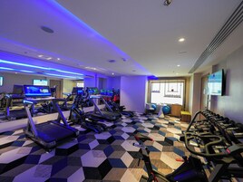 Une salle de sport équipée de tapis de course, de vélos d’appartement et de divers appareils d’exercice.