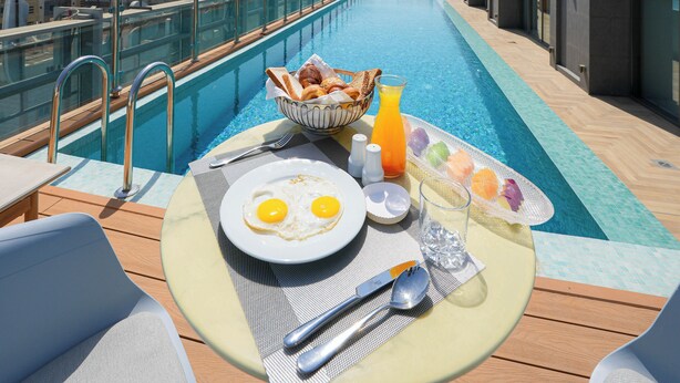 A rooftop pool area with a breakfast setup including eggs, toast, and juice. - Casa Di Ora Hotel Al Rawdah (Jeddah)