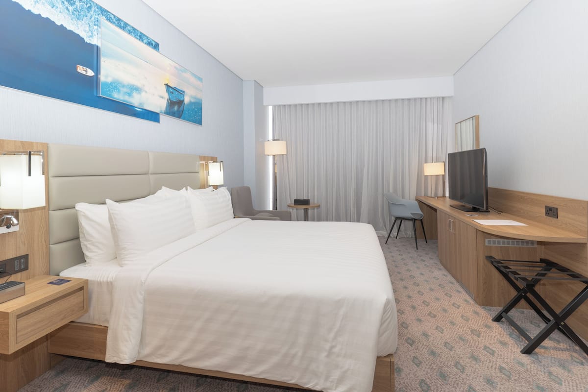 A hotel room with a large bed, a desk, a television, and a small table.