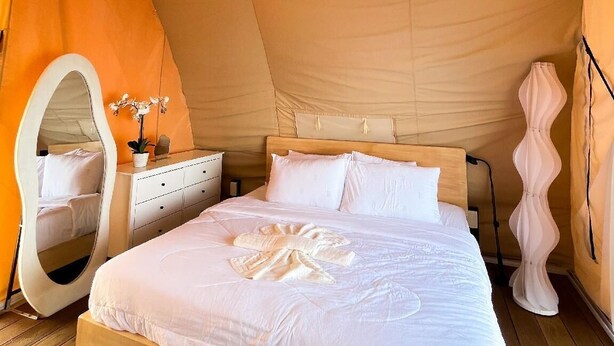 A tented room with a bed, bedside table, mirror, and hanging lights. - Floating Home in Reef Resort Unit 11 (Samal)