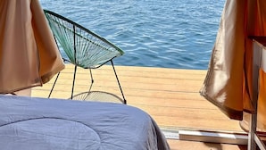 A tent with a view of the sea, a chair, and a bed.