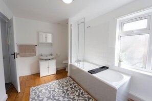 Une salle de bain moderne équipée d’une baignoire, d’une douche à parois de verre, d’un lavabo et de toilettes.