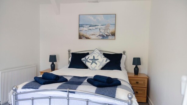 A neatly made bed with a checkered blanket, two pillows, and two bedside lamps.