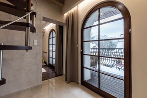 Ein modernes Interieur mit einer Treppe, großen Bogenfenstern und Blick auf eine verschneite Landschaft.