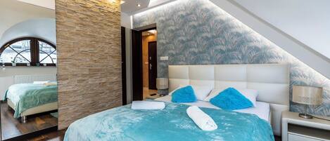 A modern bedroom with a large bed, a stone accent wall, and a ceiling with recessed lighting.