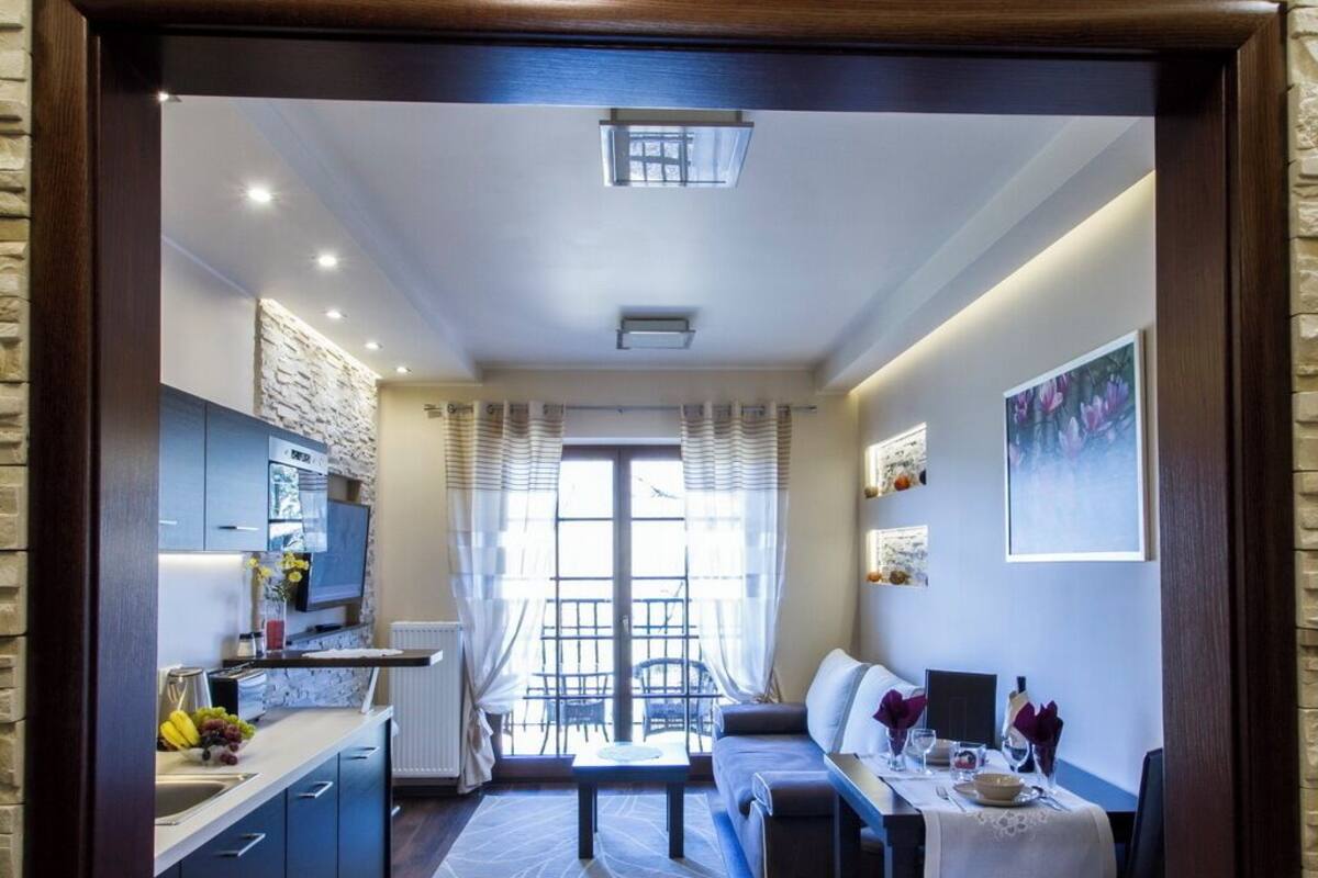 Una cocina moderna con una pared de acento de piedra, un comedor con una mesa preparada para dos personas y un sofá.