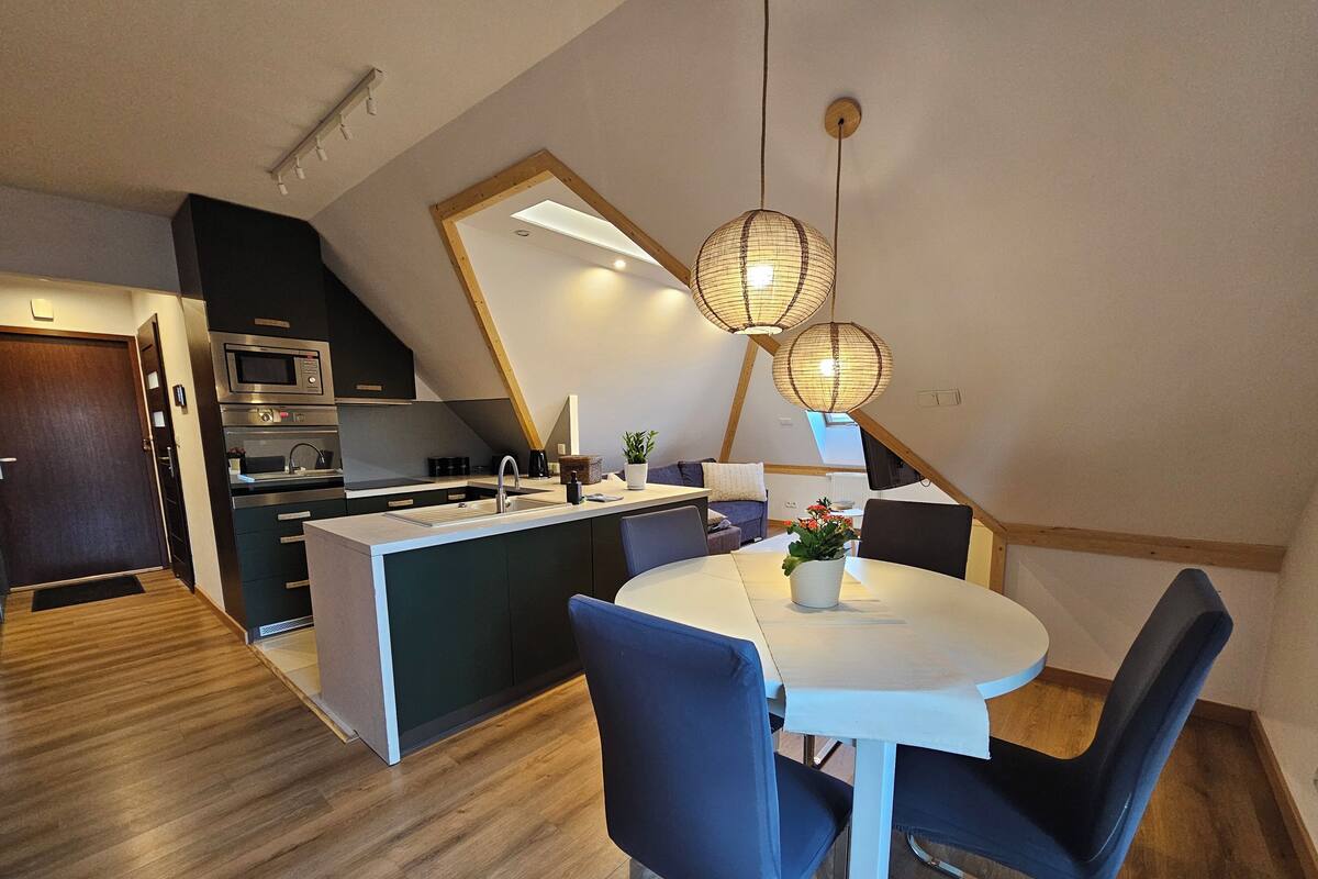 Una cocina moderna con una isla central, muebles oscuros y un comedor con una mesa redonda y sillas.