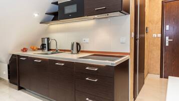 A modern kitchen with dark wooden cabinets, a stainless steel sink, and a built-in microwave.