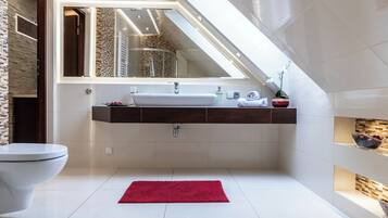 A modern bathroom with a white sink, a mirror above it, and a red rug on the floor.