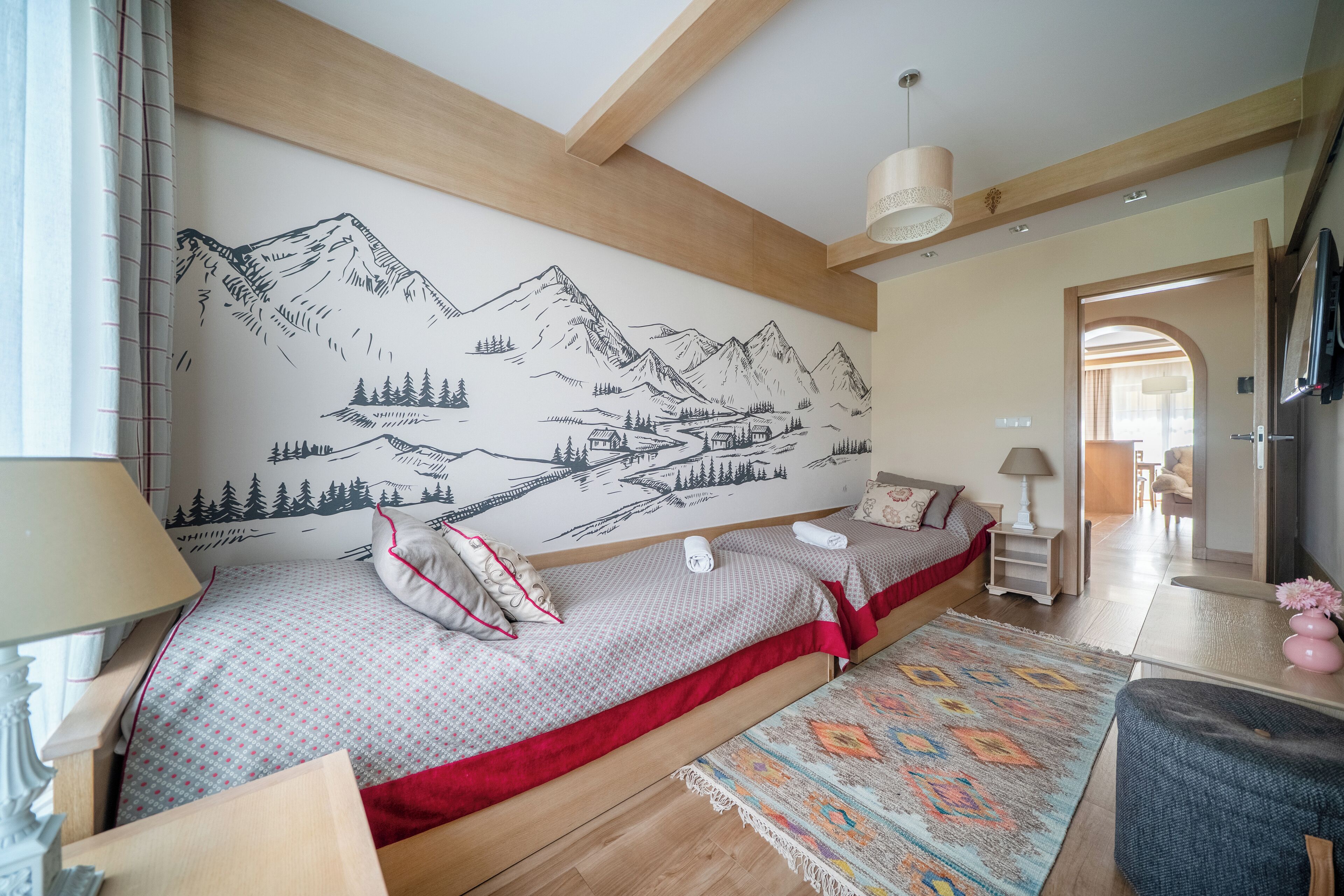 Un dormitorio con cama, mesita de noche, lámpara, cómoda y un mural en la pared.