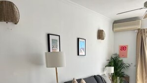 Una sala de estar moderna con un sofá gris oscuro, una mesa de comedor de madera con un tazón, y una lámpara de pie.