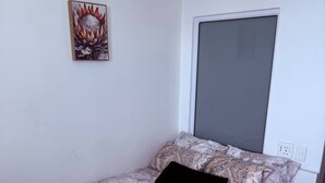 A bedroom with a bed, a window, and a wall-mounted picture. - Chick and Luxurious Studio (Cape Town)