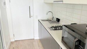 A modern kitchen with a stainless steel stove, a microwave, and a sink with a faucet. - Chick and Luxurious Studio (Cape Town)