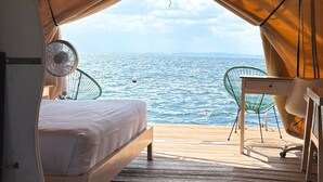 Ein Zelt mit Bett, Tisch und Stuhl, mit Blick auf das Meer.