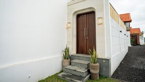 A modern house with a wooden door, two potted plants, and a small set of steps leading to the entrance. - Casa Lova - Luxury 2 BR Villa with Pool (Munggu)