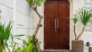A modern house with a wooden door, a stone pathway, and a small garden with tropical plants. - Casa Lova - Luxury 2 BR Villa with Pool (Munggu)