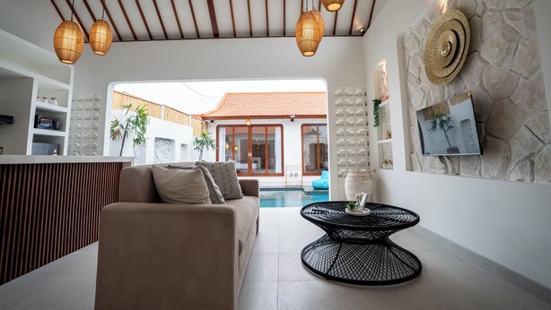 A modern living area with a sofa, a round table, and a ceiling fan. - Casa Lova - Luxury 2 BR Villa with Pool (Munggu)