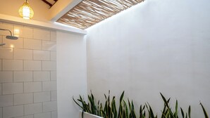 A modern bathroom with a white bathtub, a shower, and a plant wall. - Casa Lova - Luxury 2 BR Villa with Pool (Munggu)