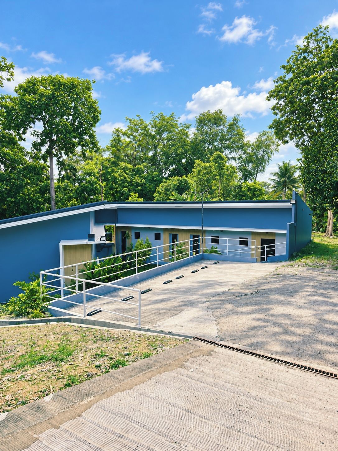 A building with a blue exterior, a covered outdoor area, and a staircase leading to the entrance.