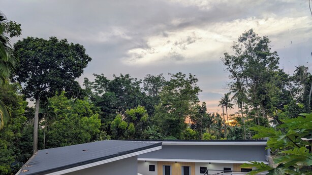 A modern building with a grey roof and a small attached structure. There is a black car parked in front. - The Canyoneer Inn (Alegria)