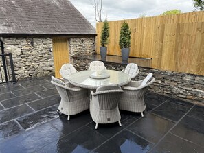 A round outdoor patio with wicker furniture and a stone wall backdrop.