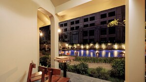 An outdoor patio area with a pool, wooden chairs, and a table. - La Sen Village (Nam Hoa Lu)