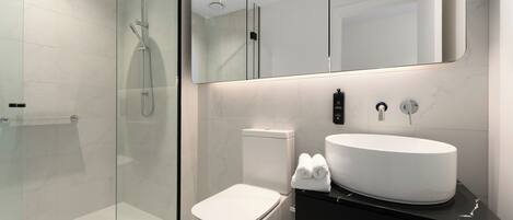 A modern bathroom with a glass-enclosed shower, a white toilet, and a vanity with a large sink.