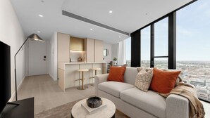 Una sala de estar moderna con un sofá, una mesita de centro y vistas a la ciudad a través de amplias ventanas.
