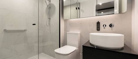 A modern bathroom with a glass-enclosed shower, a white toilet, and a black vanity with a white sink.