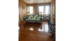 A living room with a sofa, a dining area with a table and chairs, and a kitchen area. - Heart of Downtown Hilo (Hilo)