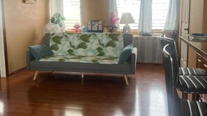 Un salon avec un canapé, un coin repas avec une table et des chaises, et un espace cuisine.