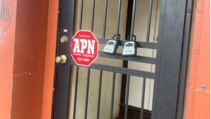 A door with a metal security bar and a sign that reads "APN" and a phone number. - Heart of Downtown Hilo (Hilo)