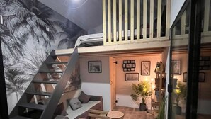 A modern interior with a wooden staircase, a seating area with a table, and a wall decorated with framed pictures. - Maisonnette and terrace in the heart of the village to do everything on foot in St Mandrier (Saint-Mandrier-sur-Mer)