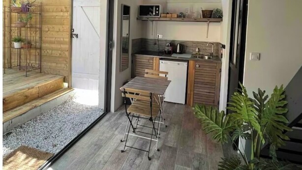 A modern kitchen with a dining area, wooden flooring, and a large window. - Maisonnette and terrace in the heart of the village to do everything on foot in St Mandrier (Saint-Mandrier-sur-Mer)