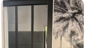 A room with a large window, a geometric patterned wall, and a mural of palm trees. - Maisonnette and terrace in the heart of the village to do everything on foot in St Mandrier (Saint-Mandrier-sur-Mer)