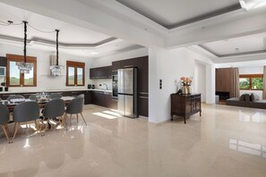 Un'ampia cucina con elettrodomestici moderni, una zona pranzo con sedie e un soggiorno con divano.